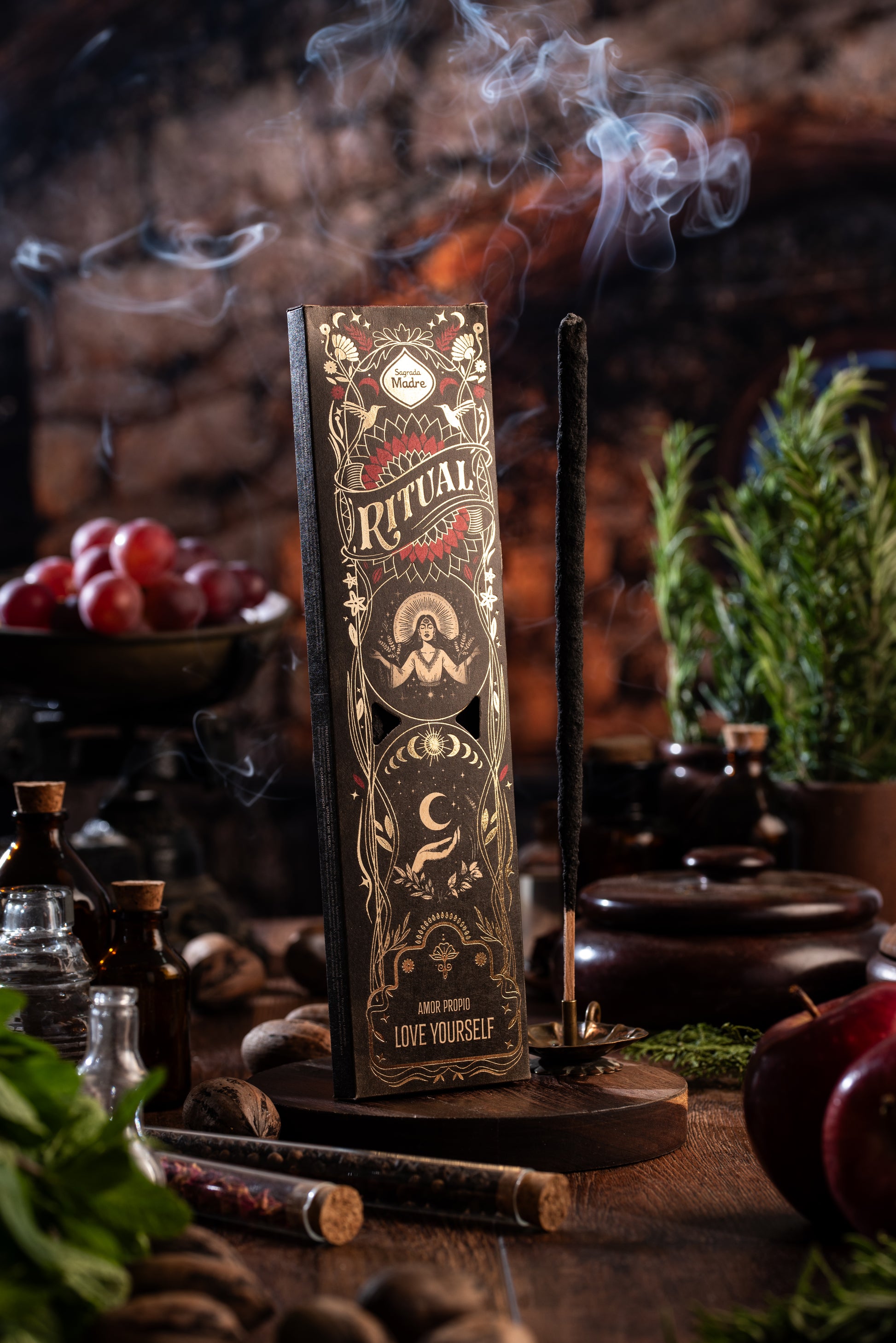 Sagrada Madre Ritual Love Yourself – Räucherstäbchen mit Rauch und Holzuntergrund, Ritualszene mit Kräutern und Fläschchen