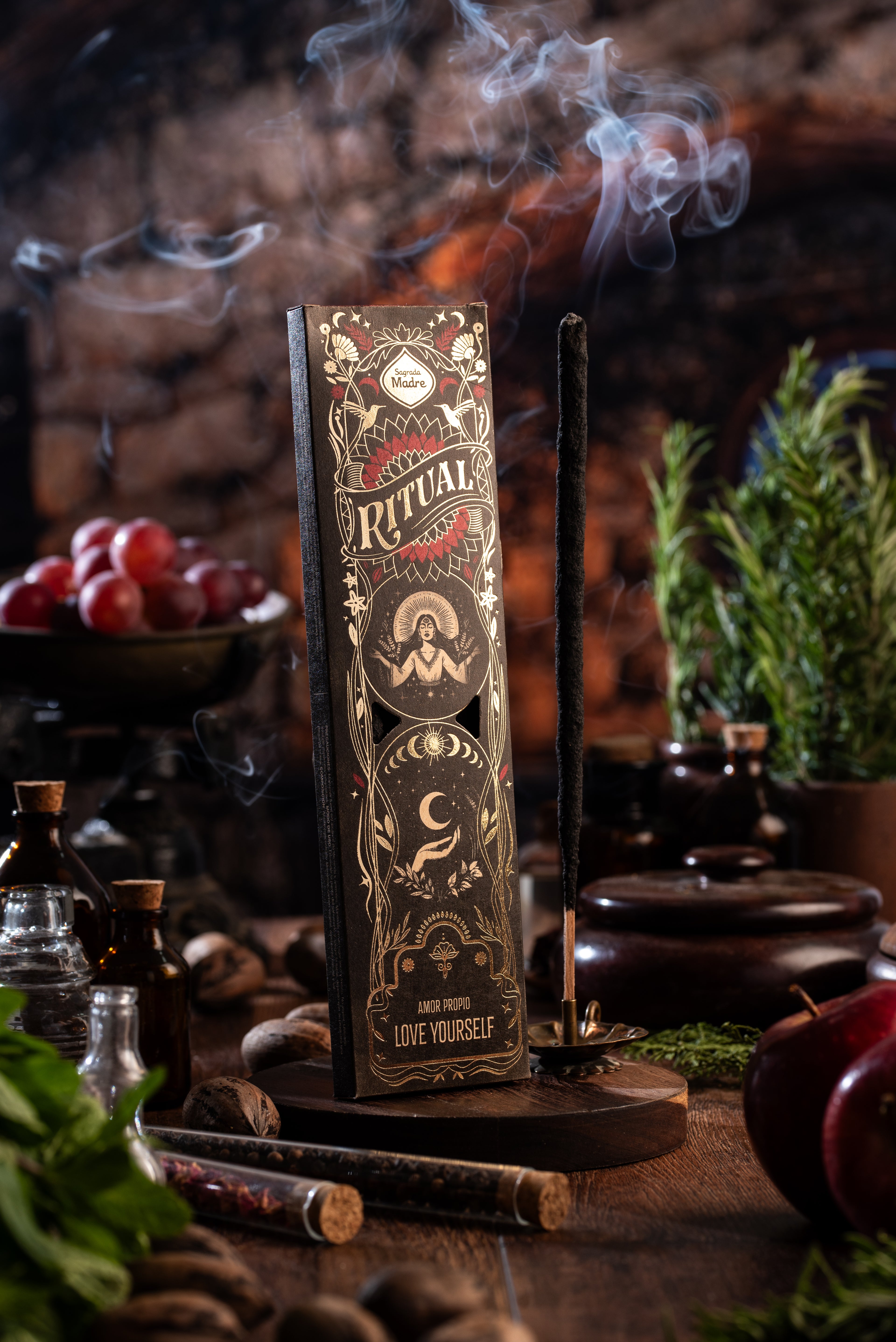 Sagrada Madre Ritual Love Yourself – Räucherstäbchen mit Rauch und Holzuntergrund, Ritualszene mit Kräutern und Fläschchen