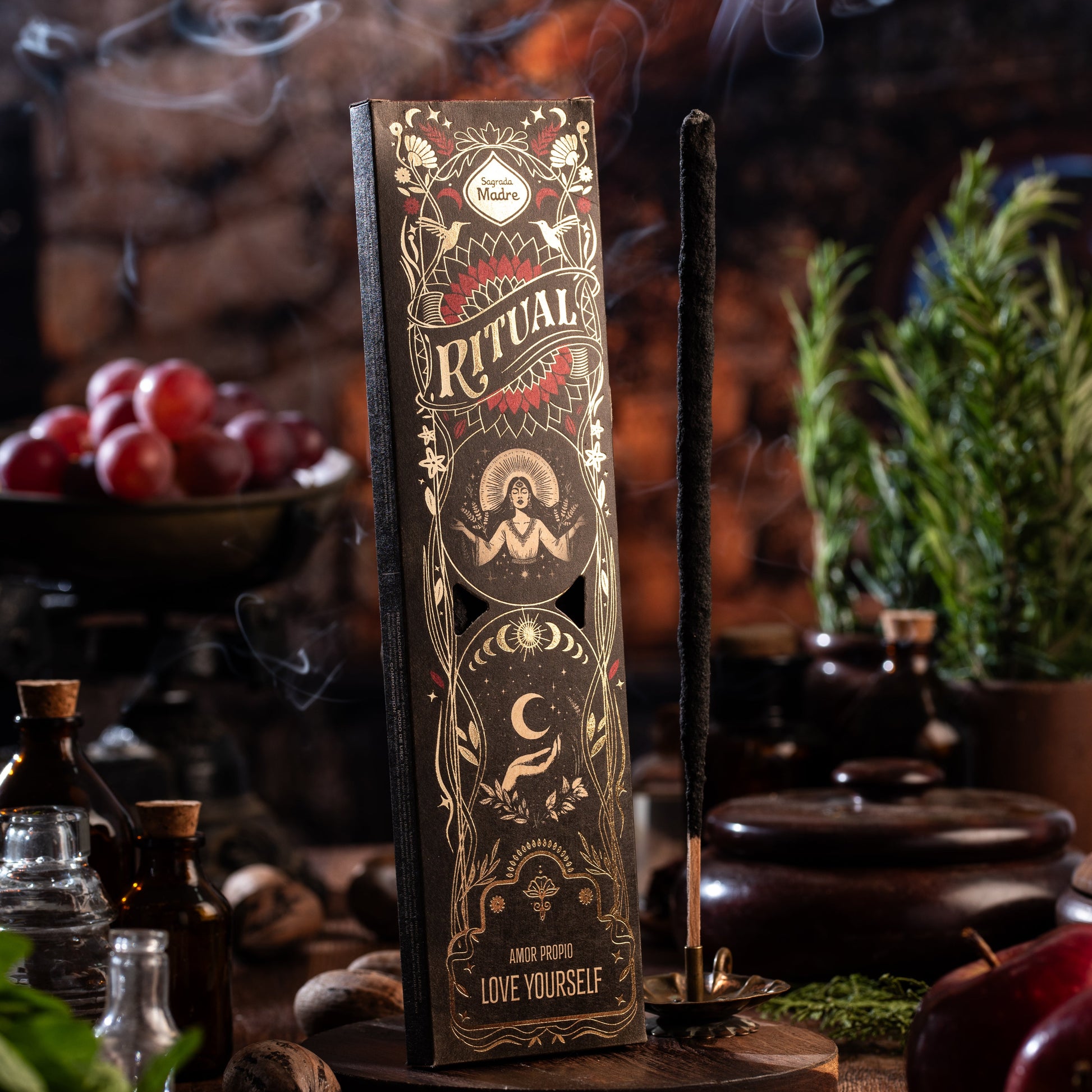 Sagrada Madre Ritual Love Yourself – Räucherstäbchen mit Rauch und Holzuntergrund, Ritualszene mit Kräutern und Fläschchen
